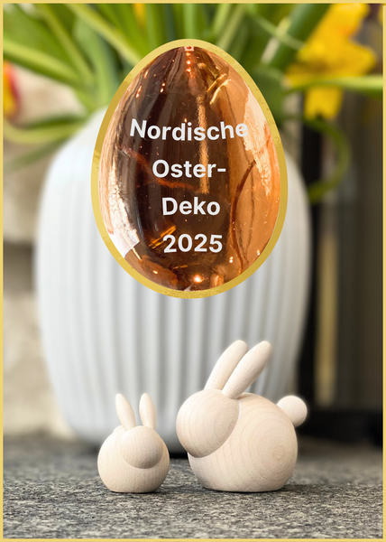 Nordische Oster-Deko und wie sie gut gelingen kann. Hier die kleinen Holz-Hasen von aarikka Pupunen und Pupu aus Finnland vor der Kähler-Hammershoi Vase in weiß aus Dänemark. In einem orangenen Glas-Ei von iittala steht der Titel des Posts. 