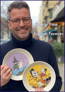 Torben mit den beiden neuen Mumin Klassiker Tellern von Moomin Arabia: Friends forever (Snufkin, Klein My und Moomin auf lila-blauem Hintergrund) und Family Time (Moomin Mama, Moomin Papa und Moomin auf gelbem Hintergrund)